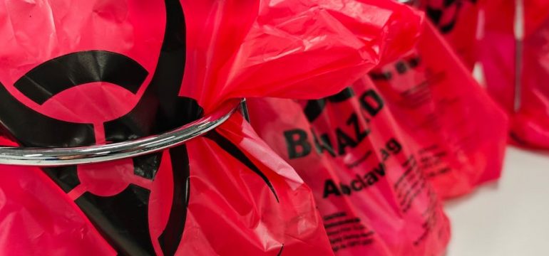 A group of red biohazard waste bags with a large biohazard symbol