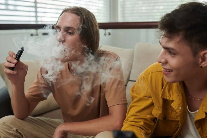 An image of young adults sharing a vape to illustrate how meningitis-causing pathogens are transmitted through shared saliva-contact items