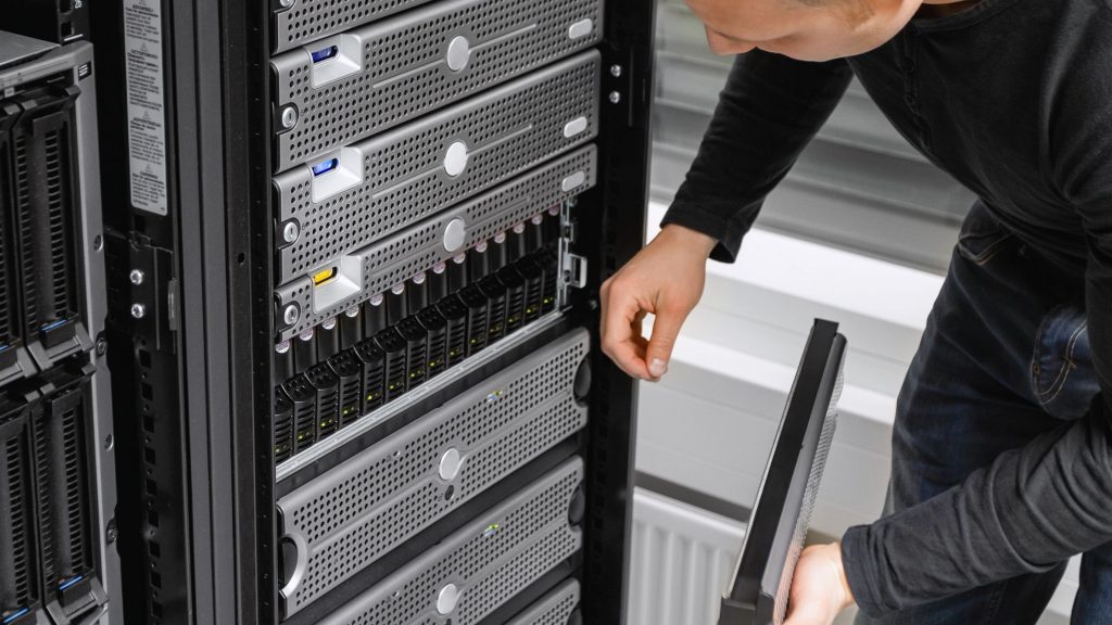 A worker in a data centre inspects a rack of servers